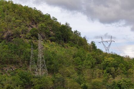 Image of high voltage electricity pylon and transmission power line with sky and mountain...