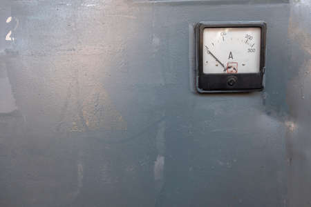 vintage electricity switch gauge on a gray metal door. rough surface texture