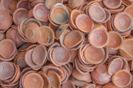 many red brown ceramic small plates lying in a pile. rough surface textureの写真素材