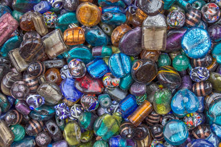 multi-colored glass gems with holes lie in a heapの写真素材