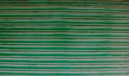 green old horizontal stripes of metallic blinds with rust and paint smudgesの写真素材