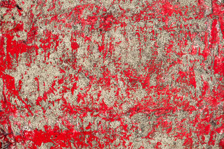 old gray concrete wall with bright red paint spots. rough surface texture