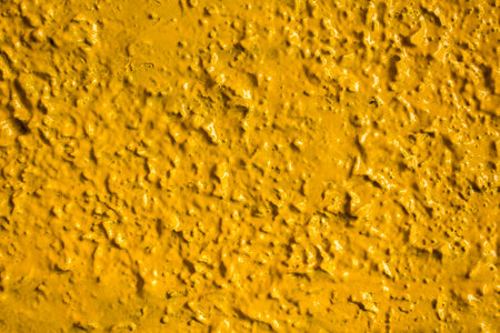 bright yellow relief wall with highlights of light and shadows close-up. rough surface texture