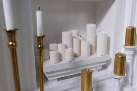 white round wax candles of different sizes on a white shelf
