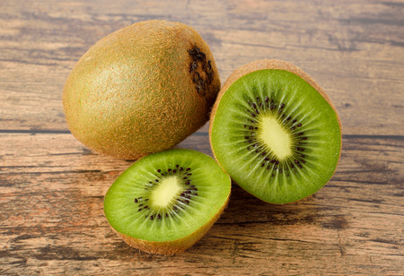 closeup whole and sliced kiwi fruit on wood table backgroundの写真素材