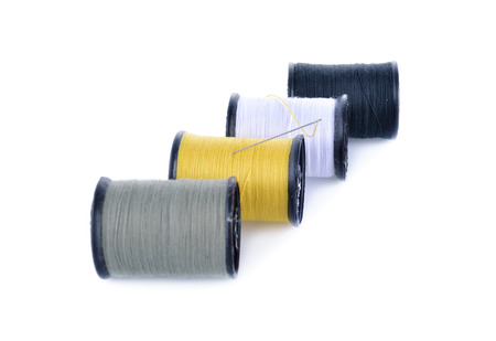 spool of thread and needle on white background