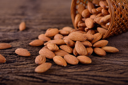 almond seed in basket and on wooden tableの写真素材
