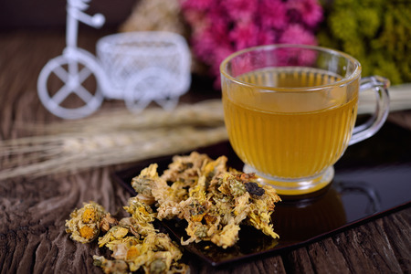 a cup Chrysanthemum tea on black plate and on wooden backgroundの写真素材