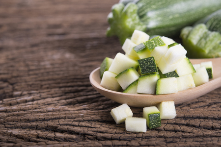 whole and cube cut fresh zucchini on wooden backgroundの写真素材