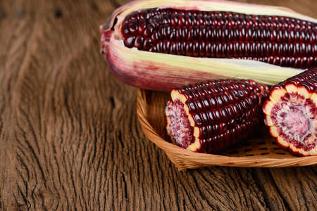 fresh purple corns in the basket on wooden backgroundの写真素材