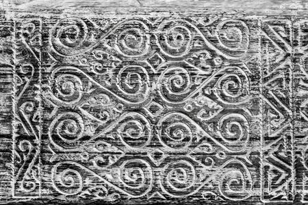 Wooden black and white background. Scrolls and spirals carved in wood. Aged wood surface. Painted in...