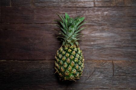 Top view of a ripe fresh pineapple lying on a wooden brown background. Juicy fruit for a great healthy diet.の写真素材