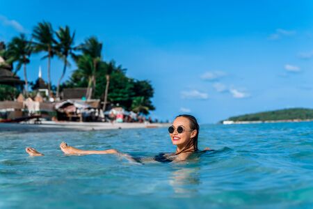 An attractive young girl is bathing in the calm sea on the beach in clear turquoise sea water....