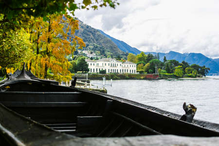 The Coast Of Lake Como, Northern Italy. Villa on the lake. A small fishing boat in the foreground....