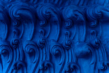 A bas-relief element in the form of sea waves at the base of the Buddha statue in a Buddhist temple. Abstract Indigo background. Blue Ocean waves.の写真素材
