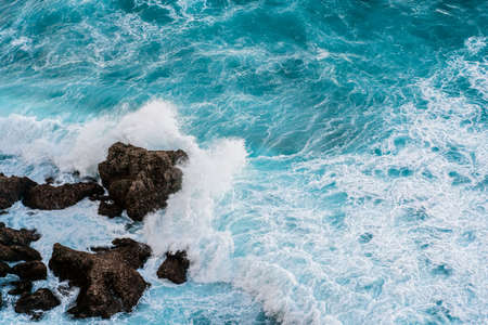 Powerful ocean waves break on the rocky shore. Aerial survey of the coastline of the island of Bali....