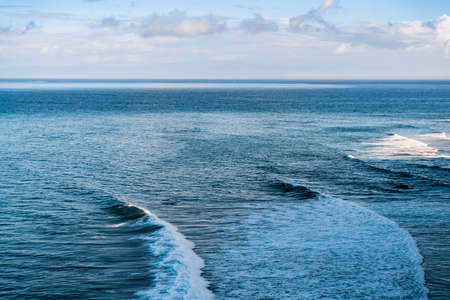 Aerial shot of powerful ocean waves in Bali. The surface of the ocean off the coast of the Bukit Peninsula. The surf spot. Sunny weather and cloudy skiesの写真素材