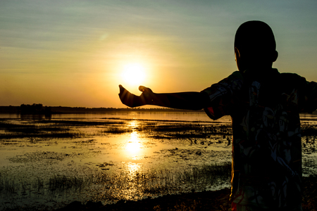 children show your hand  and holding the sun, with sunset backgroundの写真素材