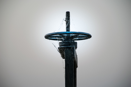 Old black wheel for drain water or floodgate , evening sky backgroundの写真素材
