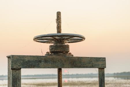 Old black wheel for drain water or floodgate , evening sky backgroundの写真素材