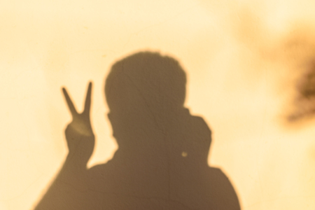 dark shadow man in the house wall, brown wall background, and show handの写真素材