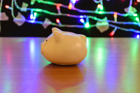 a container for saving money in, especially one shaped like a pig, with a slit in the top through which coins are rich,piggy bank on wooden blurring dot color backgroundの写真素材
