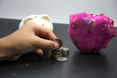 piggy bank and pink heart is isolated ,with hand safe coin for piggy bank,black and white background...