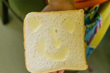 Bread made with condensed milk, will be smile shape on face of bread and be  happiness for children eating,one hand holding breadの写真素材