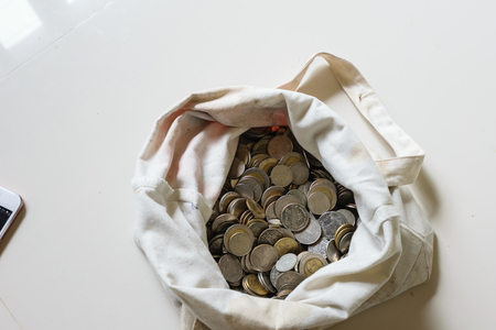 There are silver coins gold coins in an old white bag.white backgroundの写真素材