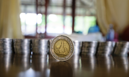 There are coins of one study placing it upright on the table beautifully wood in the House. The background is  blurring,concept business imageの写真素材