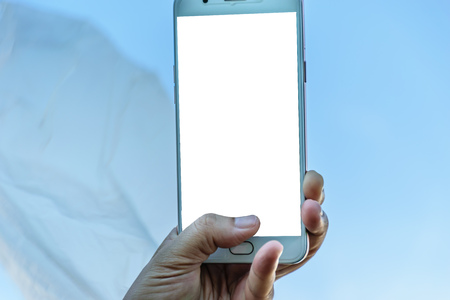 one hand holding smart phone shooting blue sky,surface on smart phone is white backgroundの写真素材