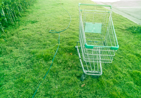 Shopping cart with green plant background on car park.の写真素材