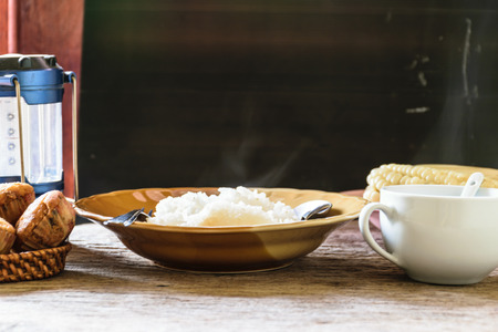 hot rice cooker with hot steam. Placed on a wooden table near the window. And the hands are scooped.の写真素材