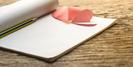 Note love on paper with old wooden background, and pink heart shape above it, Valentine's day texture background concept.の写真素材