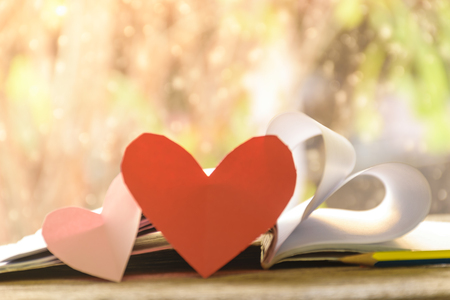 Note love on paper with old wooden background, and pink heart shape above it, Valentine's day texture background concept.の写真素材