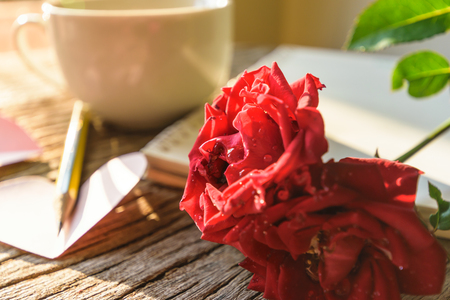 Writing note love, red rose and note and pencil on old wooden and sun lighting passed window in the morning, lovely and feeling warm heart, Valentine's day aconcept.の写真素材