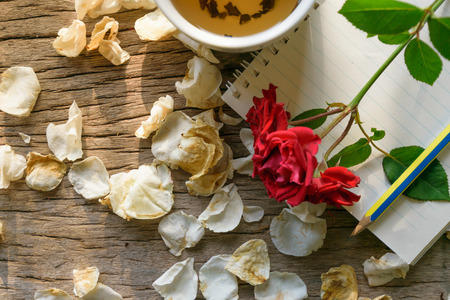 Writing my love, cup tea , note red flower and white petal rose flower put on old wooden table with sunlight, Valentine's day concept.の写真素材