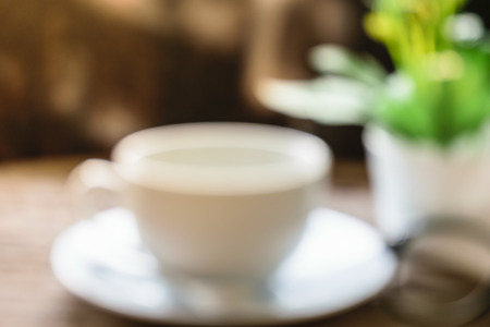 blurred feeling warm lovely, hot cup tea , red rose , note and pencil put on old wooden table in the morning, sun ray passed windowの写真素材