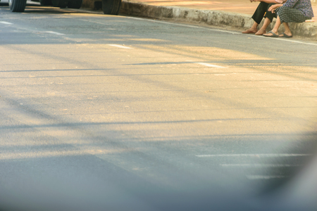 Soft sun lighting on floor road with people sit down shoulder road, in the countryside city market, in the evening time.の写真素材