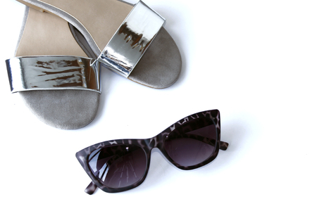 Silver summer sandals and sunglasses, white background.の写真素材