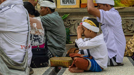 Bali, Indonesia - september 2017 : Balinese people with their son is praying fervently during...