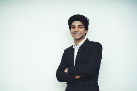 Portrait of a Young Handsome Asian Business man wearing black coat and white shirt standing in front of a white background, smiling and looking into the cameraの写真素材