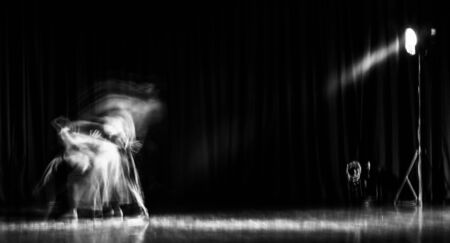 An artistic dancer in a theater shot with a slow shutter speed in order to achieve the desired motion blur.の写真素材