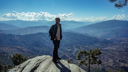 A young traveler standing on a cliff in a canyon with layers of mountain in backgroundの写真素材