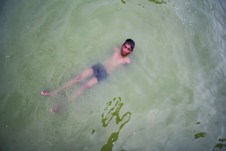 Delhi, New Delhi, India - May 26 2020: A small kid swimming in a lake filled with green water near India Gate. Cheerful and carefree children.のeditorial素材