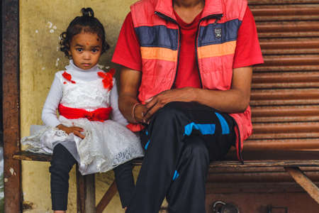 Almora, Uttrakhand, India- May 22 2020: A travel Portrait of a young girl sitting with her dad without his head in the frame.のeditorial素材