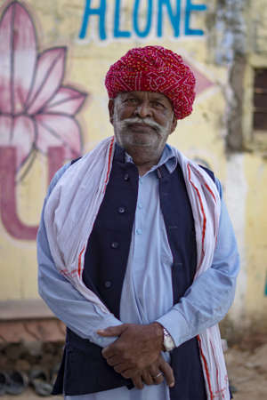 Pushkar, Rajasthan / India- June 5 2020 : Old man in white kurta wearing a turban standing looking directly into the camera.のeditorial素材