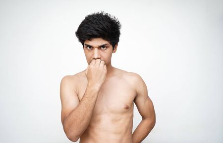 Young handsome shirtless indian boy being cautious, biting his nails.の写真素材