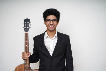 Young handsome asian boy wearing formal and specs holding a guitarの写真素材