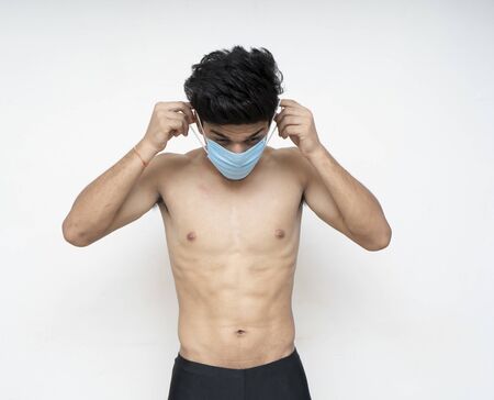 Young asian shirtless fitness model wearing a blue mask for protection from corona virusの写真素材